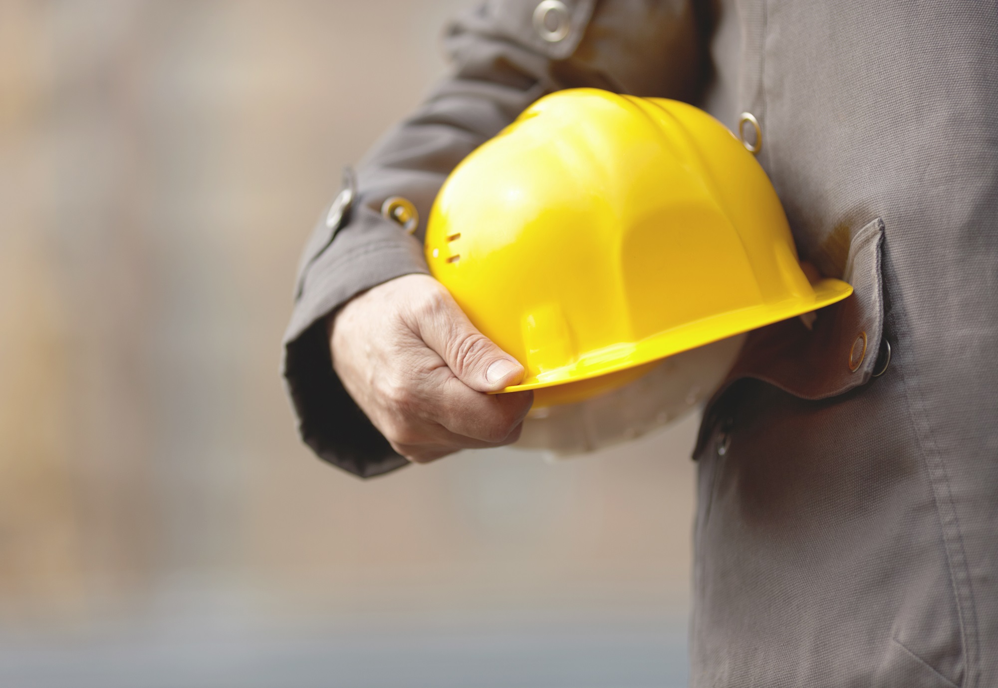Hand of builder with yellow hardhat, natural light,selective focus
