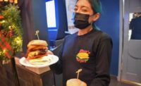 A server at Steve's Burgers in North Bergen where's a mask while delivering food to a table. - STEVE'S BURGERS