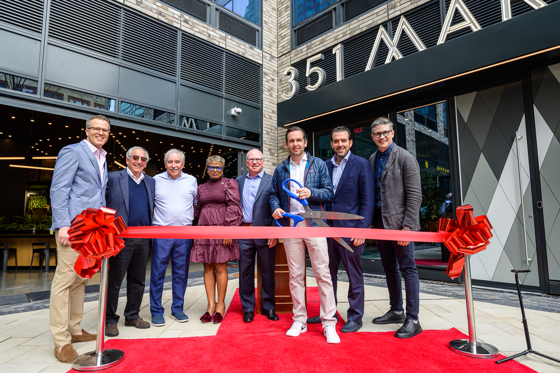 From Left, KRE Group COO Jeremy Kaplan, KRE Group Founder Murray Kushner, KRE Group Partner Jeff Persky, Jersey City Council President Joyce Watterman, Northwestern Mutual Real Estate Senior Director Matt Ascher, Jersey City Mayor Steven Fulop, KRE Group President Jonathan Kushner, and KRE Group Design Director Marc Kushner cut a ribbon at 351 Marin in Jersey City to celebrate lease up of the luxury rental building in the city's Powerhouse Arts District on May 12, 2022.