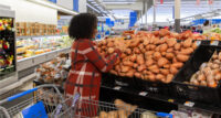A Walmart customer shops for sweet potatoes.