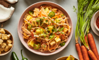 The Red Coconut Curry is prepared with rice noodles, roasted tofu, pineapples, jalapeños, carrots, scallions, cilantro, and the brand's own red coconut curry sauce. - HONEYGROW
