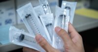 A health care worker holds syringes.