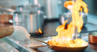 Chef cooking vegetables in wok pan.