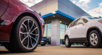 Automotive Dealership Store. New and Pre Owned Vehicles in Front of the Showroom Building. PHOTO: DEPOSIT PHOTOS