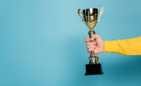 Cropped view of man holding golden trophy on blue